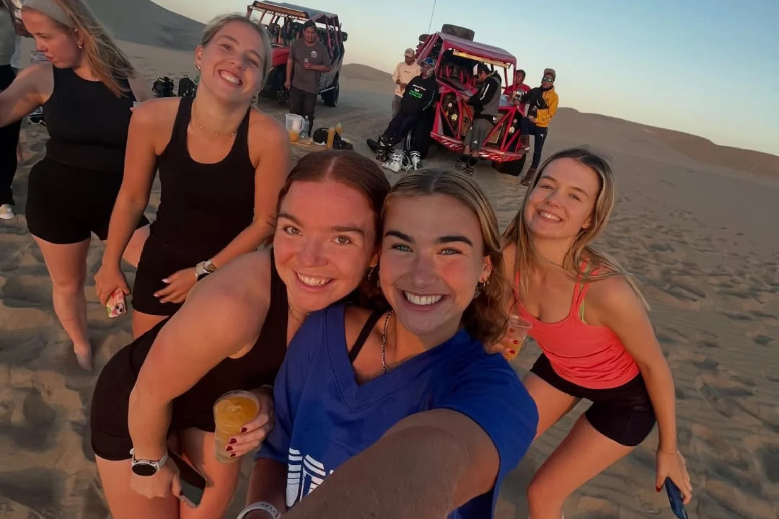 Group of travelers happy after the dune buggy in Huacachina desert dunes in Ica Peru – adventure sandboarding and buggy tour in famous Peru oasis - Wayki Bus - Paracas to Huacachina Bus