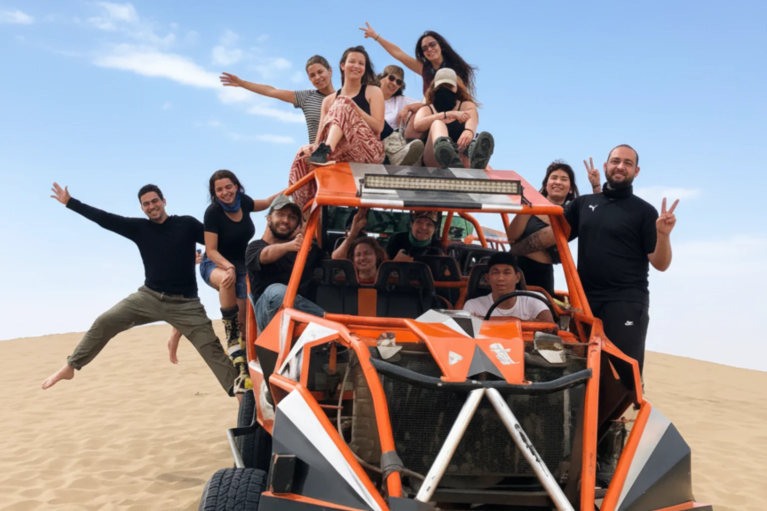 Group of travelers riding dune buggy in Huacachina desert dunes in Ica Peru – adventure sandboarding and buggy tour in famous Peru oasis - Wayki Bus - Lima to Huacachina Bus